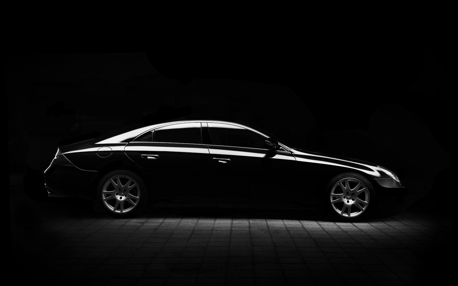 Black coupe lit against a dark studio backdrop