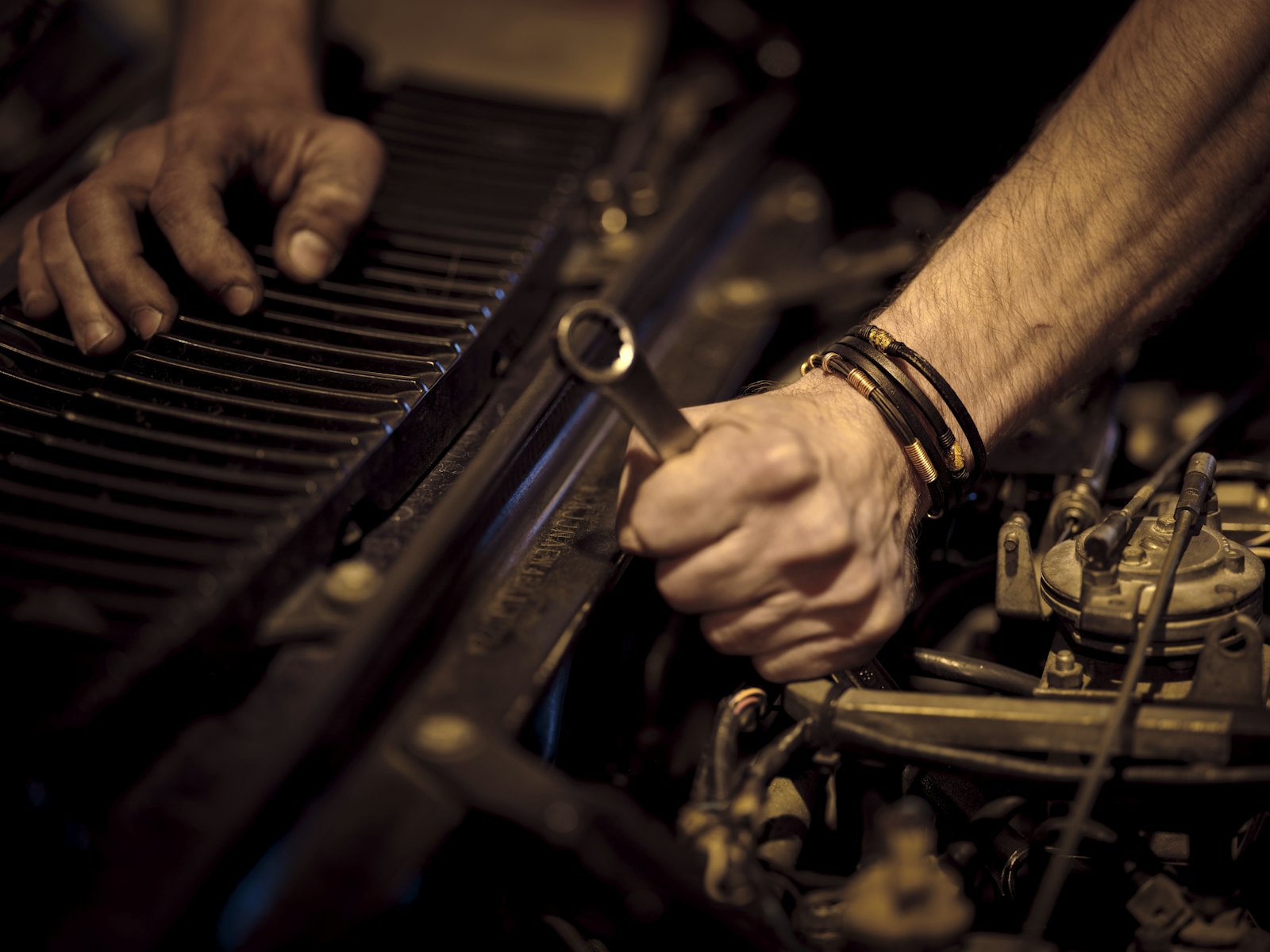 Hands working a wrench on an engine