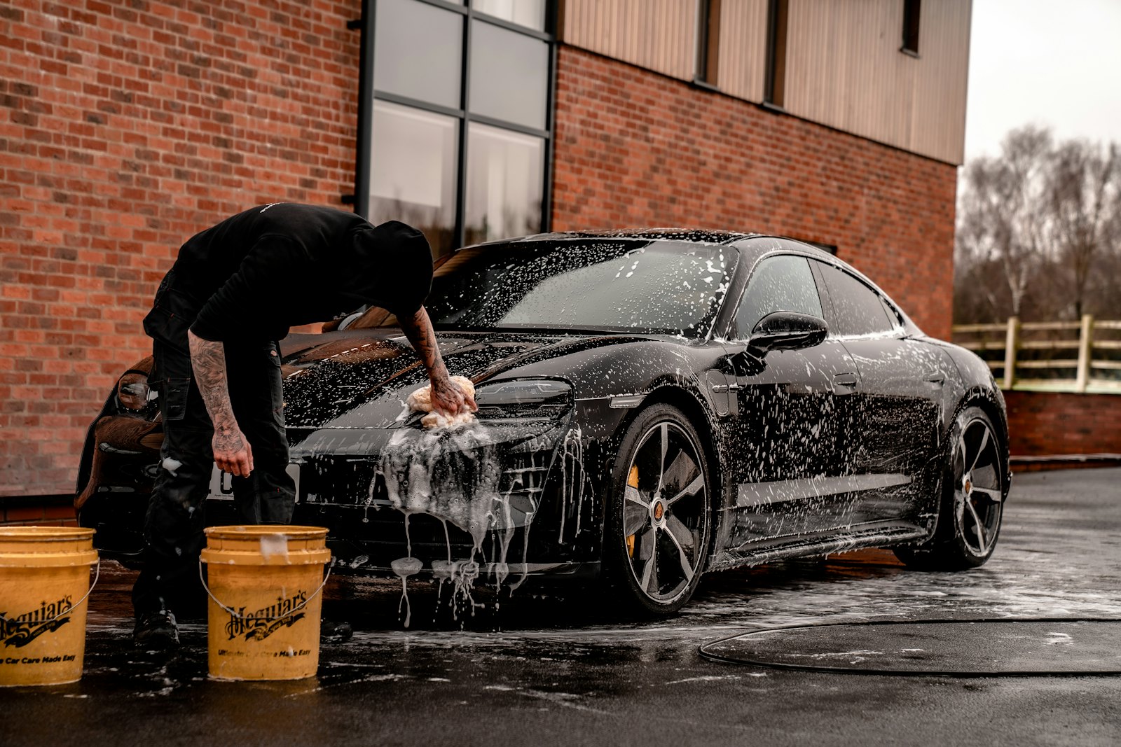 Hand-washing a black sports car before paint correction