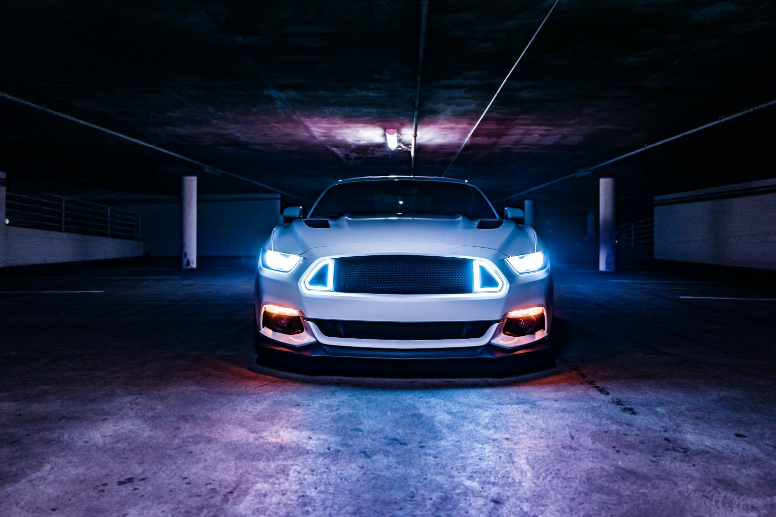 Ford Mustang GT with headlights on in a dark garage