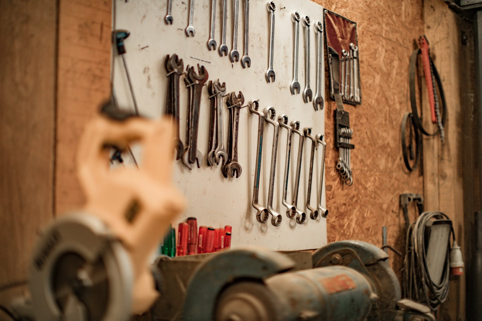 Wall of well-used wrenches above a bench vise in the shop